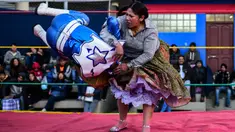 Pegulat Bolivia, Ana Luisa Yujra (kanan) membanting lawannya pegulat pria di atas ring gulat di El Alto, pada 24 November 2019. Di Bolivia ada sebuah atraksi gulat yang diperankan perempuan dengan menggunakan busana khas warga Bolivia. (Ronaldo SCHEMIDT / AFP)