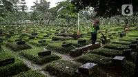 Petugas kebersihan menyapu area makam di Tempat Pemakaman Umum (TPU) Karet Bivak, Jakarta, Minggu (27/6/2021). Pemerintah Provinsi DKI Jakarta membatasi aktivitas dan kunjungan ke TPU hingga 5 Juli 2021 untuk menekan penularan COVID-19. (Liputan6.com/Faizal Fanani)