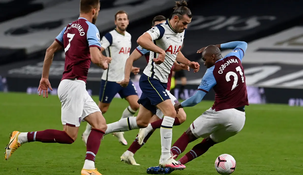 Penyerang Tottenham Hotspur, Gareth Bale mengontrol bola melewati pemain West Ham, Angelo Ogbonna dalam laga Liga Inggris di Tottenham Hotspur Stadium, Minggu (18/10/2020). Laga yang berakhir dramatis 3-3 itu diwarnai debut bintang anyar Tottenham, Gareth Bale. (Neill Hall/Pool via AP)
