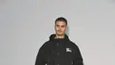 Romeo Beckham tampil kasual dengan jaket hoodie teknikal hitam berlogo kuda Burberry, celana lebar hitam, dan sneakers putih [dok. Burberry]