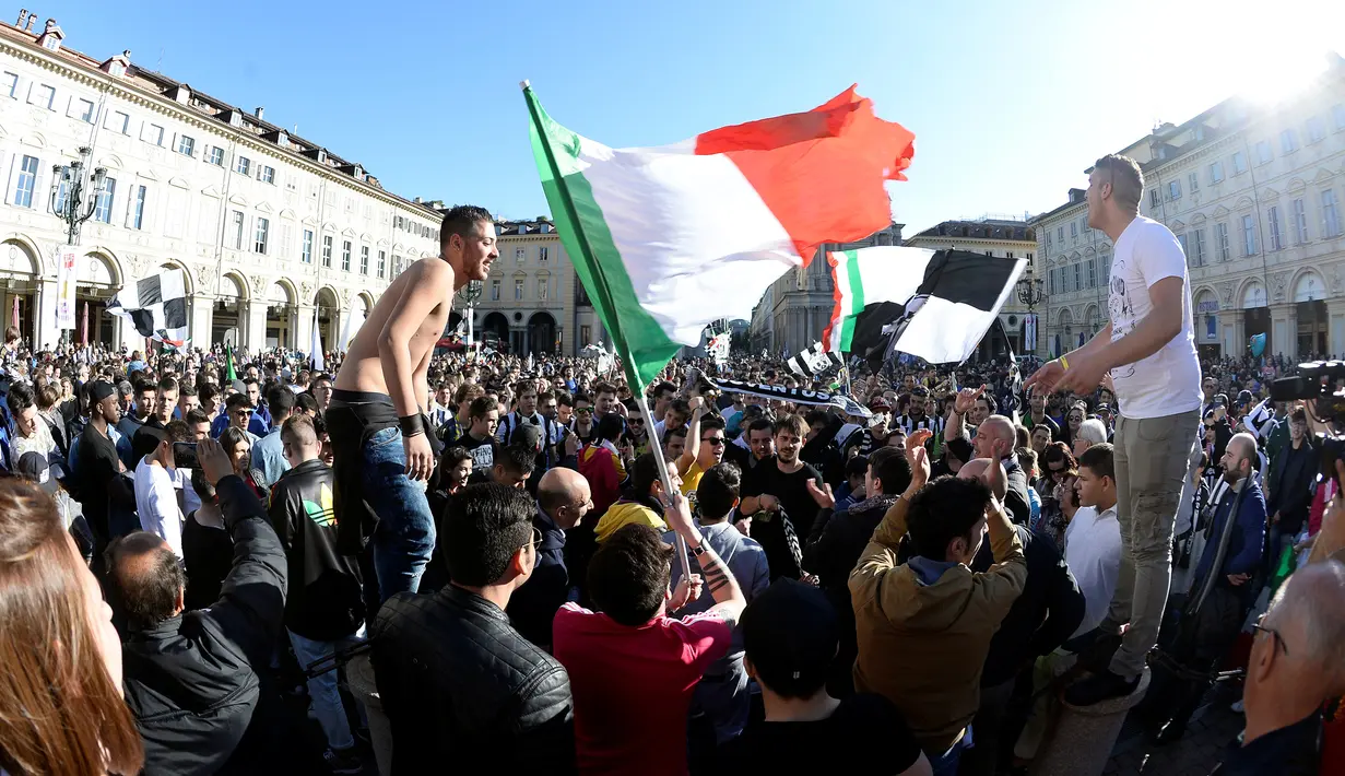 Suporter Juventus mengibarkan bendera Itali merayakan kemenangan usai merebut gelar Serie A Italia di pusat kota Turin, Italia (25/4). Juventus sukses meraih lima gelar juara Serie A dalam lima musim beruntun. (REUTERS/Giorgio Perottino) 