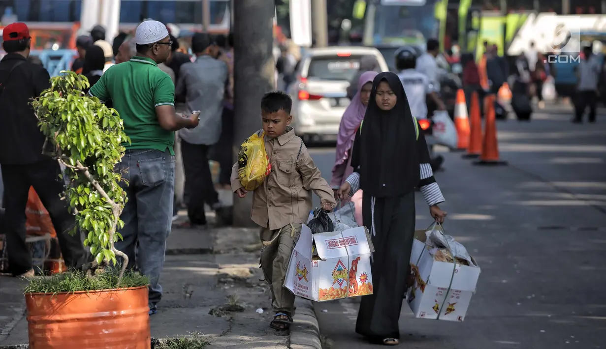 Penumpang membawa barang usai usai turun dari bus AKAP di Terminal Kampung Rambutan, Jakarta, Selasa (19/6). Empat hari setelah Lebaran, jumlah penumpang yang tiba di Terminal Kampung Rambutan mencapai 17.492 orang. (Liputan6.com/Faizal Fanani)