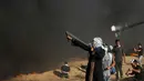 Pengunjuk rasa wanita Palestina menembakkan batu menggunakan ketapel ke arah tentara Israel saat bentrok di Khan Younis, perbatasan Gaza, Jumat (10/8). (AP Photo/Adel Hana)