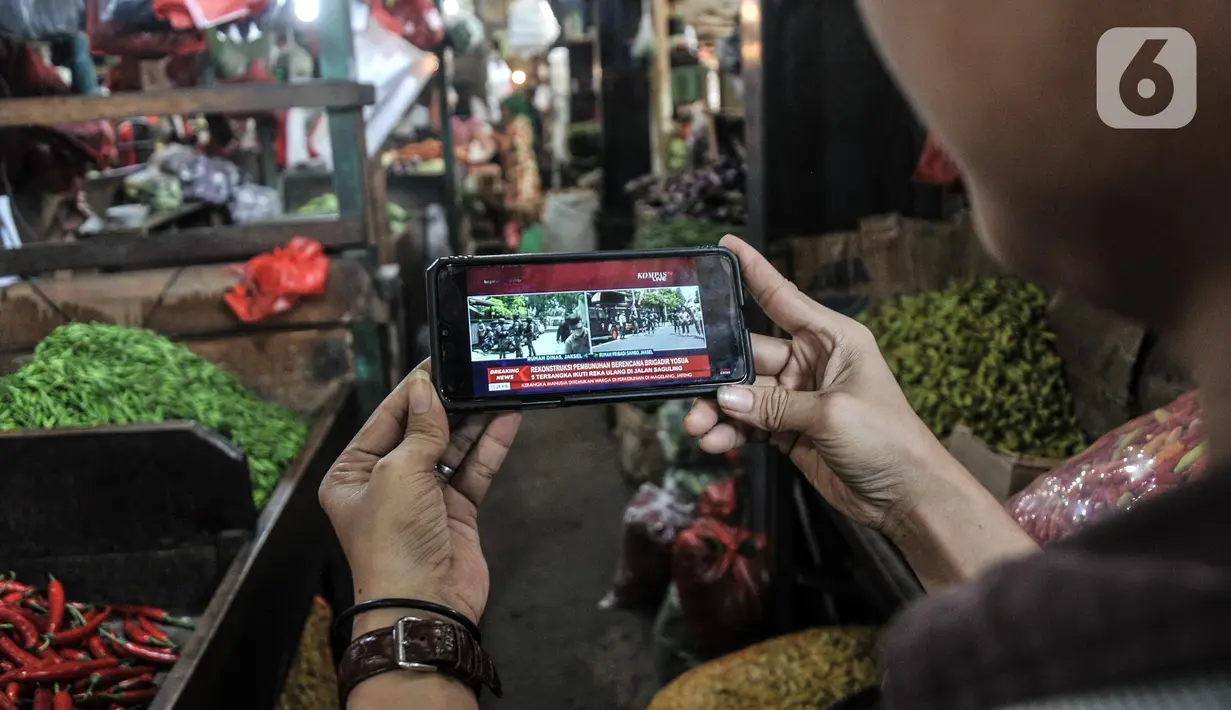 Pedagang menyaksikan tayangan pada gawainya yang menyiarkan langsung rekonstruksi pembunuhan Brigadir Nofriansyah Yosua Hutabarat alias Brigadir J melalui smartphone di Pasar Senen, Jakarta Pusat, Selasa (30/8/2022). Rekonstruksi ulang pembunuhan Brigadir J yang dihadiri oleh lima tersangka, yakni Ferdy Sambo, Bharada Richard Eliezer (Bharada E), Bripka Ricky Rizal, Kuat Ma'ruf, dan Putri Candrawathi itu menjadi perhatian warga dari berbagai kalangan untuk menyaksikan secara langsung meski hanya melalui siaran televisi atau gawai. (merdeka.com/Iqbal S. Nugroho)