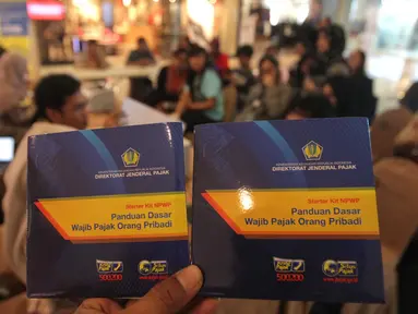 Masyarakat memperlihatkan kartu pajak di salah satu pusat perbelanjaan di Jakarta, Jumat (11/3). Mengacu data Kementerian Keuangan, kinerja penerimaan pajak negara dalam dua bulan pertama tahun 2016 masih loyo. (Liputan6.com/Angga Yuniar)