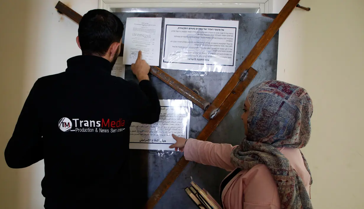 Karyawan Trans Media melihat pengumuman militer yang terpasang di pintu kantor mereka di Kota Hebron, Rabu (18/10). Pasukan Israel menggerebek perusahaan-perusahaan media di Tepi Barat dalam operasi besar-besaran memberantas penghasutan. (HAZEM BADER/AFP)