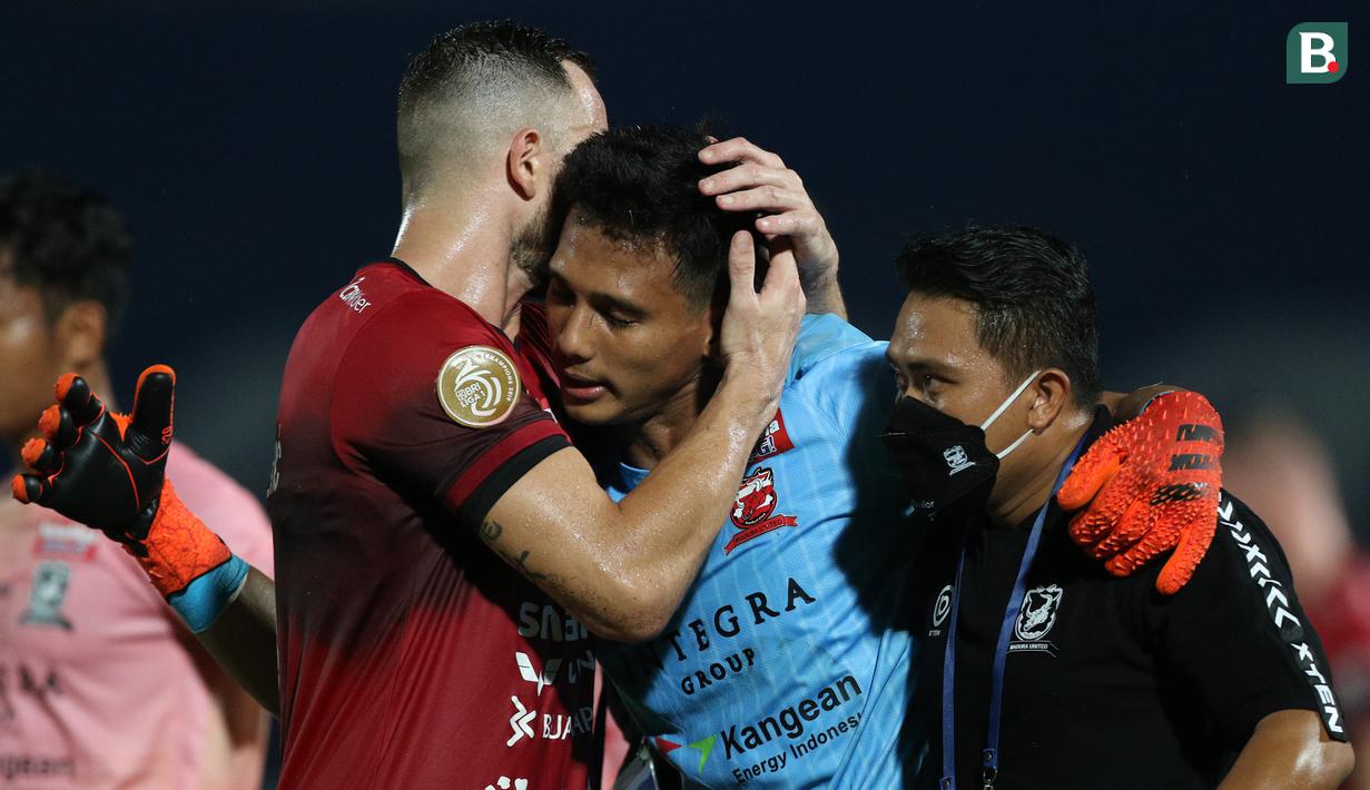 Pemain Bali United, Ilija Spasojevic (kiri) memeluk kiper Madura United, Muhammad Ridho usai mengalami cedera dalam laga pekan ke-16 BRI Liga 1 2021/2022 di Stadion Sultan Agung, Bantul, Kamis (09/12/2021). (Bola.com/Bagaskara Lazuardi)