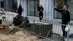 Warga mengabadikan lokasi terjadinya aksi protes depan Gedung Kementerian Pertanian Uni Eropa, Brussels , Belgia, (14/3). Aksi ini dilakukan oleh petani yang membawa sapi untuk melakukan aksi protes. (REUTERS/Francois Lenoir)
