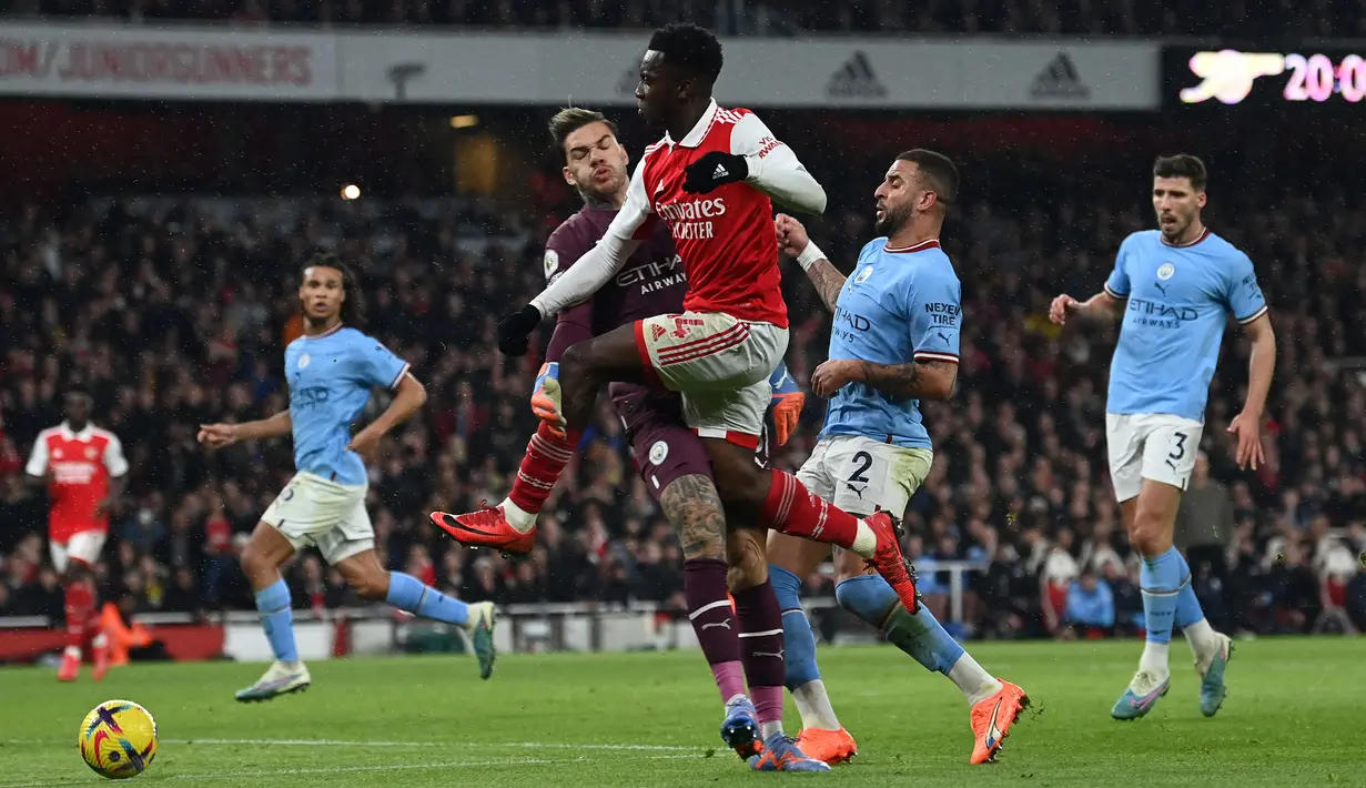 Pemain Arsenal, Eddie Nketiah (tengah kanan) dilanggar oleh kiper Manchester City, Ederson pada laga pekan ke-23 Liga Inggris 2022/2023 yang berlangsung di Emirates Stadium, London, Kamis (16/02/2023) WIB. Pelanggaran tersebut berbuah tendangan penalti untuk Arsenal. (AFP/Glyn Kirk)