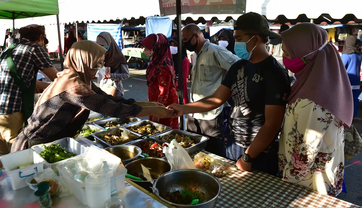 Orang-orang mengenakan masker saat membeli makanan di pasar menjelang berbuka puasa selama bulan suci Ramadan di Provinsi Narathiwat, Thailand, Selasa (5/5/2020). Ramadan kali ini berlangsung di tengah bayang-bayang virus corona COVID-19. (Madaree TOHLALA/AFP)
