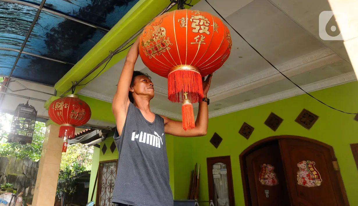 Seorang warga memasang lampion dirumahnya di Kampung Haji Bona, Depok, Jawa Barat, Kamis (19/1/2023). Bagi masyarakat Tionghoa, Imlek merupakan hari raya yang dirayakan sangat meriah oleh masyarakat keturunan China di seluruh dunia. (merdeka.com/Arie Basuki)