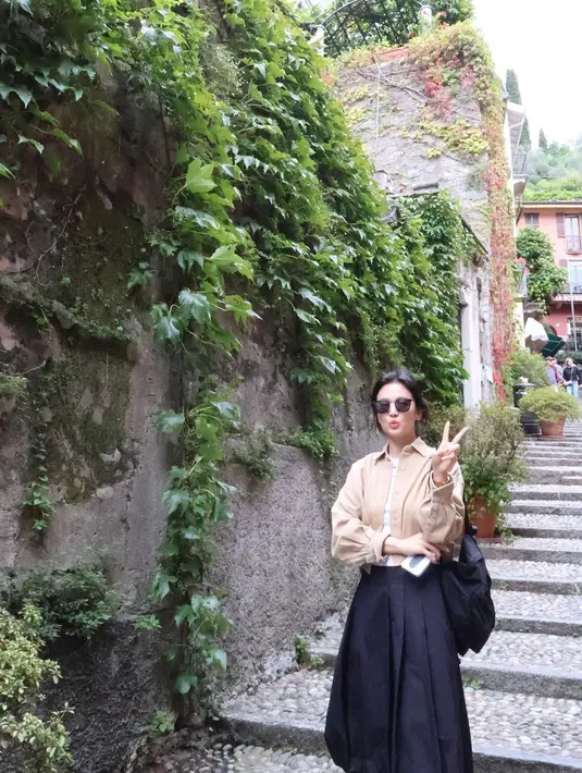 Di momen itu, ia tampil kasual dengan kaos pendek warna putih yang dipadukan jaket beige, rok hitam,  dan kacamata warna senada.