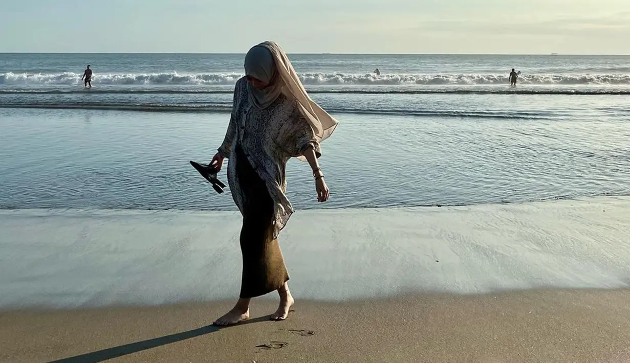Istri Egy Maulana Vikri begitu menikmati suasana pantai. Ia terlihat senang bisa menginjak pasir pantai dengan kaki telanjang. Foto ini pun banjir like dari warganet. (Liputan6.com/IG/adiba.knza)