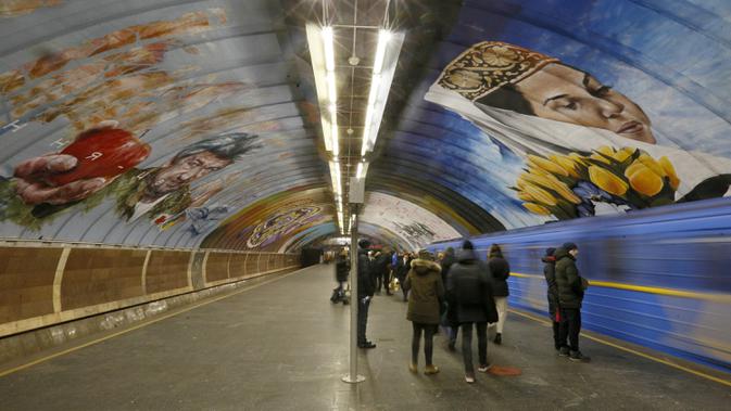 Sejumlah penumpang menunggu kereta di stasiun metro bawah tanah kota yang dipenuhi dengan mural di Kyiv, Ukraina, Rabu, (29/1/2020). (AP Photo / Efrem Lukatsky)
