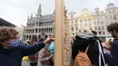 Orang-orang mengambil sejumlah balok kayu dari "The Disappearing Wall" di Grand Place, Brussel, Belgia, 3 Oktober 2020. Instalasi seni memperingati 30 tahun reunifikasi Jerman itu terdiri dari 6.000 balok kayu dilengkapi kutipan para seniman dan pemikir dari seluruh dunia. (Xinhua/Zheng Huansong)