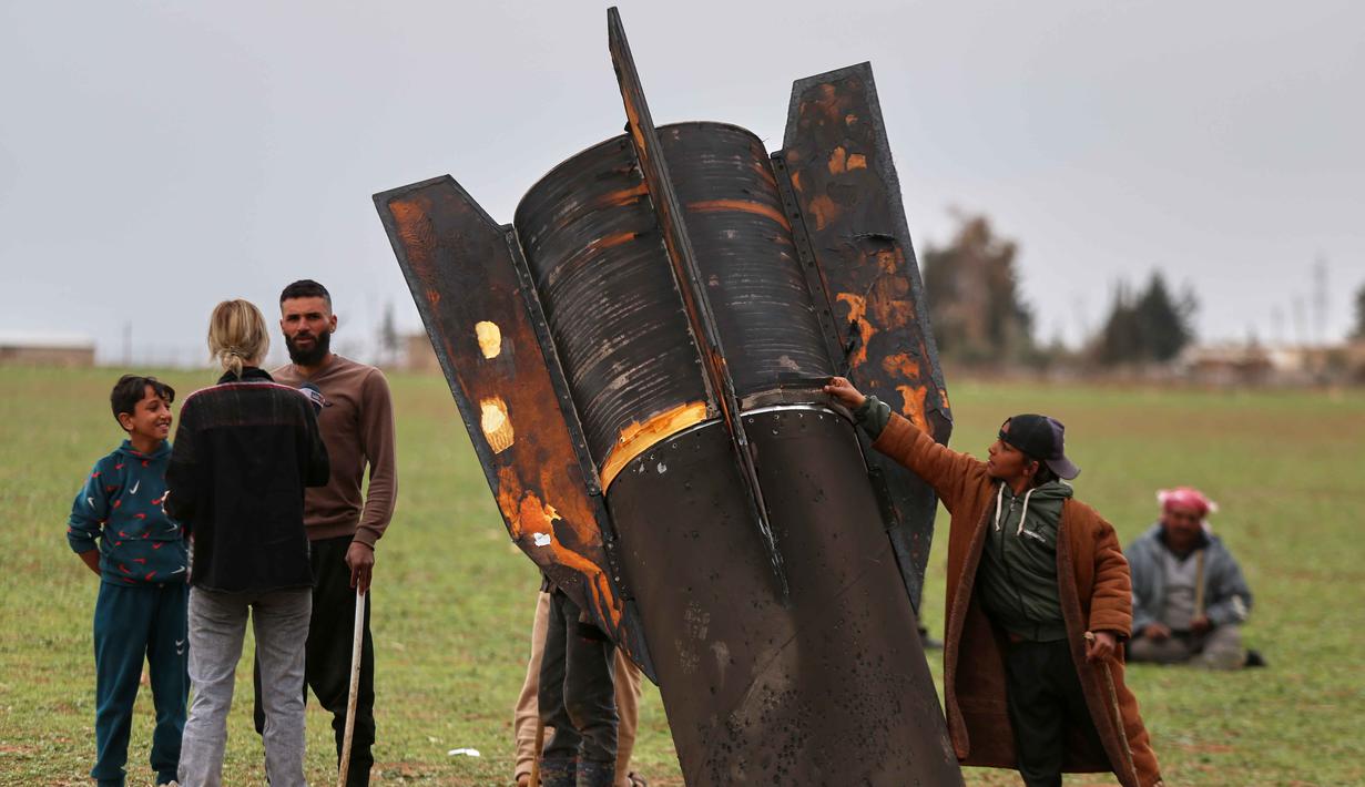 Proyektil tersebut jatuh di dekat Bandara Internasional Qamishli dan desa Dimhiyye al-Kabira yang berdekatan dengan perbatasan Turki. Tampak dalam foto, seorang anak laki-laki mempertaruhkan nyawanya dengan menyentuh proyektil rudal Iran yang belum meledak di lapangan terbuka di pinggiran Qamishli, Suriah timur, Rabu 4 Maret 2026. (AP Photo/Baderkhan Ahmad)
