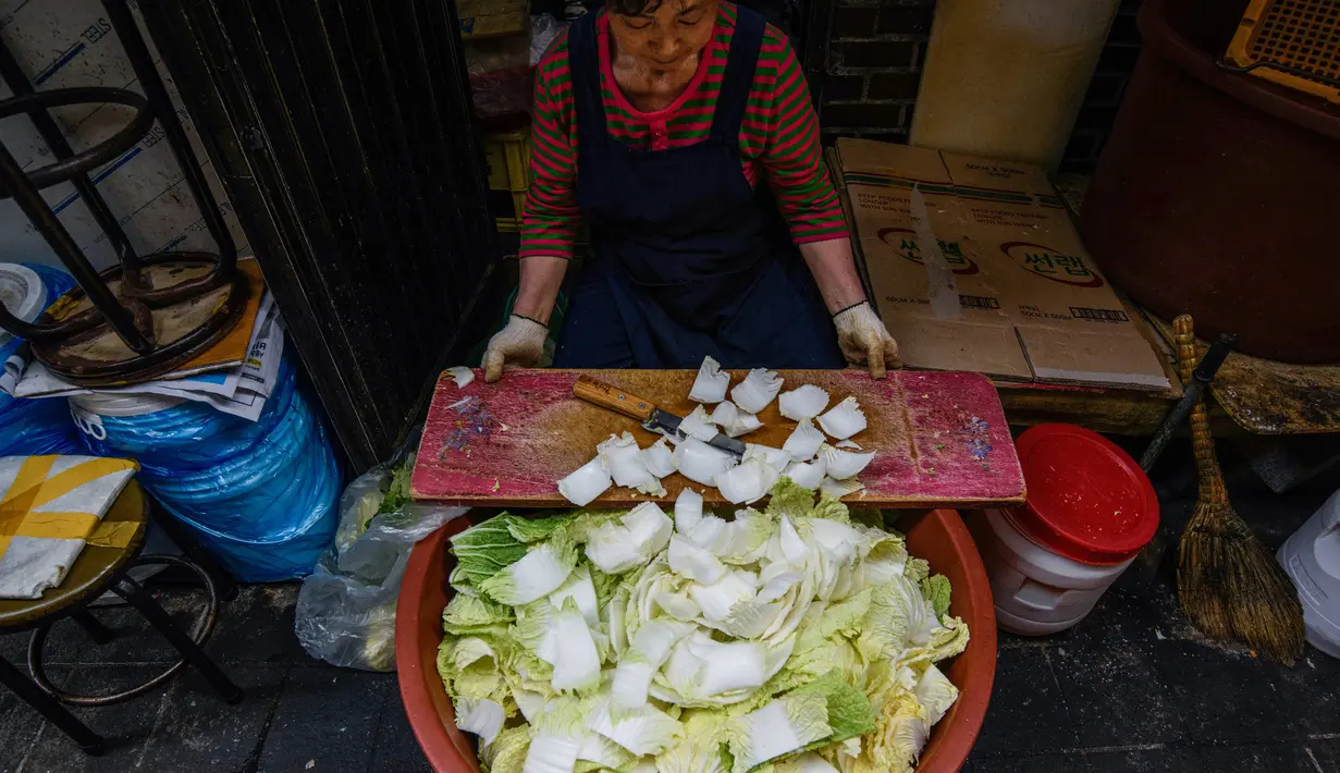 Pekerja restoran menyiapkan kubis di gang di pasar Namdaemun, Seoul (2/7/2019). Pasar Namdaemun atau Namdaemun Sijang adalah pasar yang terletak di Seoul, Korsel. Pasar ini terletak di sebelah timur Gerbang Besar Selatan (Sungnyemun) yang bersejarah dengan luas 40.000 m². (AFP Photo/Minji Suh)