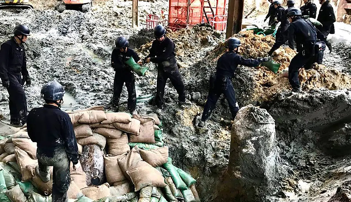 Polisi dari unit pejinak bom menempatkan karung pasir yang mengelilingi bom buatan AS yang dijatuhkan pada Perang Dunia II di persimpangan Convention Avenue dan Hung Hing Road di distrik Wan Chai di Hong Kong (11/5). (Handout / Polisi Hong Kong / AFP)