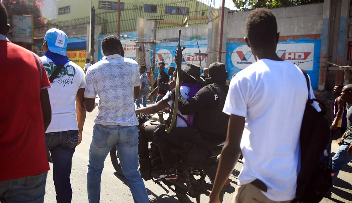 Petugas polisi bersenjata dan bertopeng bergerak maju dengan sepeda motor saat protes untuk mengecam tata kelola polisi yang buruk di Port-au-Prince, Haiti, 26 Januari 2023. Media Haiti melaporkan bahwa penculikan pun meningkat tajam di negara itu sejak awal tahun. (AP Photo/Odelyn Joseph)