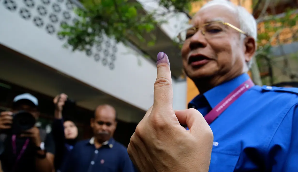 Perdana Menteri Malaysia, Najib Razak menunjukan jari yang telah diberi tinta usai memberikan hak suaranya di Pekan, Pahang, Rabu (9/5). Pemilu ini pertarungan antara PM Najib yang sudah berkuasa sejak 2009, melawan Mahathir Mohamad. (AP/Aaron Favila)