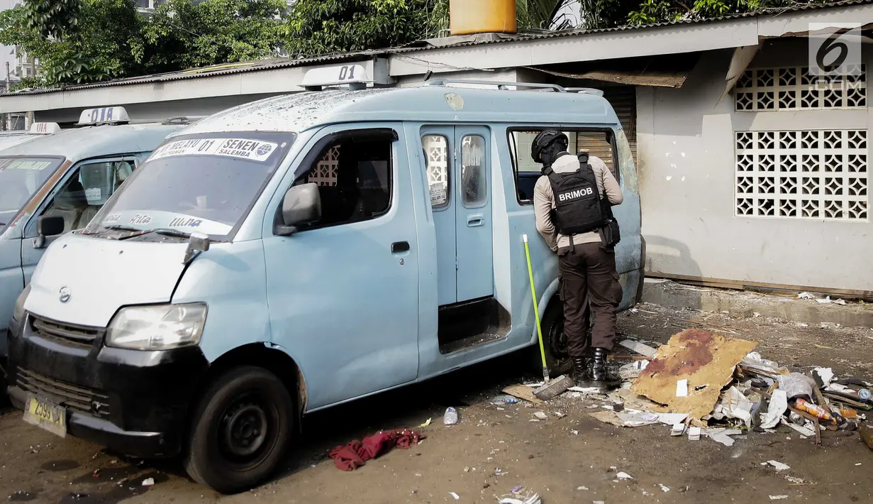 Anggota Brimob mengecek kondisi angkutan kota (angkot) yang mengalami kerusakan akibat ledakan bom di Kampung Melayu, Kamis (26/5). Angkot yang terparkir tepat di depan toilet, dekat TKP bom bunuh diri itu belum dievakuasi. (Liputan6.com/Faizal Fanani)