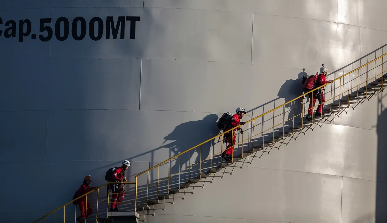 Aktivis Greenpeace menaiki tangga silo saat menggelar aksi di kilang Wilmar International di Bitung, Sulawesi Utara, Selasa (25/9). (Dhemas Reviyanto, Nugroho Adi Putera, Jurnasyanto Sukarno/Greenpeace Southeast Asia/AFP)