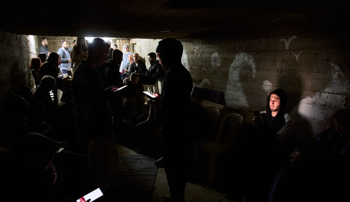Warga berlindung di tempat perlindungan bom saat sirene serangan udara memperingatkan akan datangnya serangan rudal Iran di Ramat Gan, Israel, Rabu, 25 Maret 2026. (AP Photo/Oded Balilty)