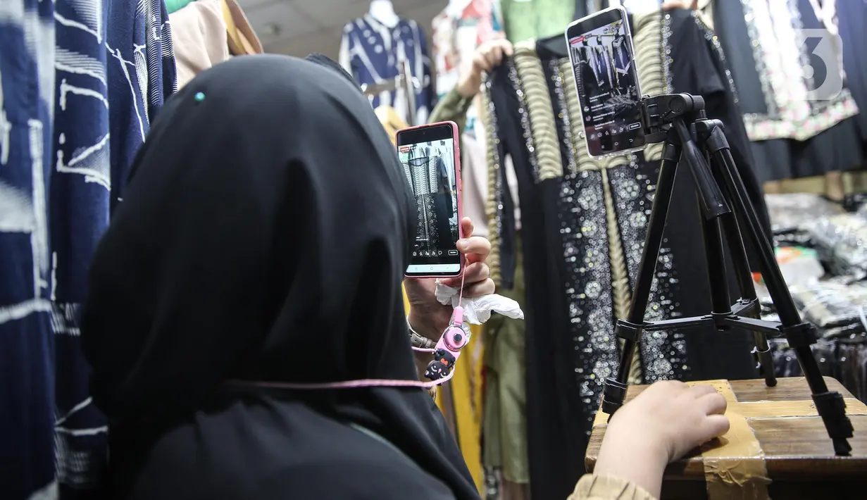 Pedagang menunjukkan sejumlah pakaian melalui aplikasi online (daring) di Pasar Tanah Abang, Jakarta, Rabu (1/7/2020). Pedagang Pasar Tanah Abang mulai menjual barang secara daring untuk menambah penjualan dan mengantisipasi turunnya jumlah pembeli di masa PSBB Transisi. (Liputan6.com/Faizal Fanani)