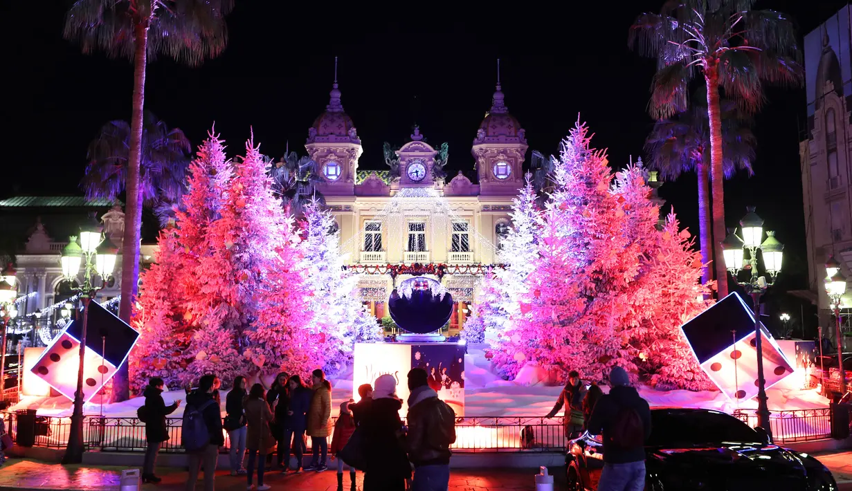 Orang-orang mengunjungi lampu dan dekorasi untuk menyambut Natal yang menghiasi depan Kasino Monte-Carlo di Monako pada 7 Desember 2018. (Photo by VALERY HACHE / AFP)