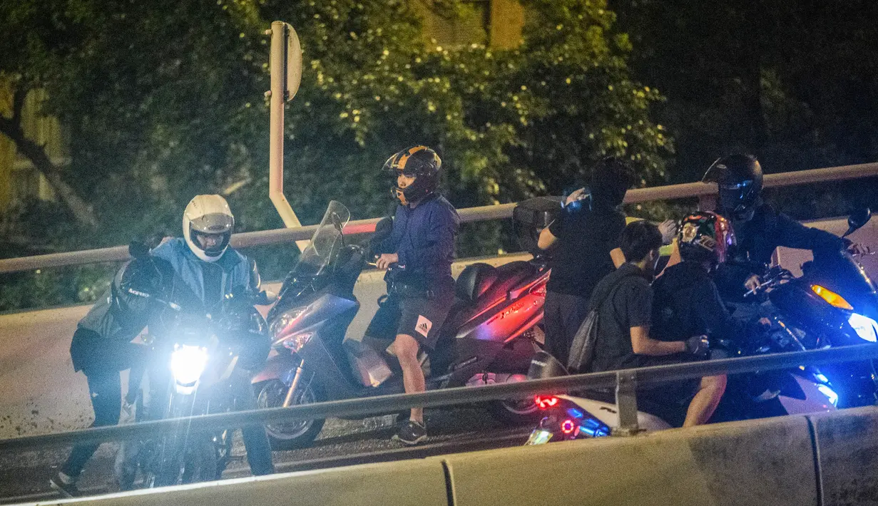 Demonstran dijemput menggunakan sepeda motor setelah menuruni jembatan menggunakan tali untuk melarikan diri dari Universitas Politeknik Hong Kong di Distrik Hung Hom, Hong Kong, Senin (18/11/2019). Lusinan demonstran berhasil melarikan diri dari kepungan polisi. (ANTHONY WALLACE/AFP)