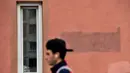 Seorang pria berjalan melewati sebuah tulisan bertuliskan "Pergi!" yang dicat dengan cat baru di dinding sebuah bangunan di Minsk (25/8/2020). Alexander Lukashenko mengklaim dirinya menang pada masa jabatan keenam dalam pemilihan yang disengketakan pada 9 Agustus. (AFP/Sergei Gapon)