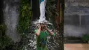 Seorang pria mandi menggunakan keran air pinggir jalan untuk mendinginkan diri di hari yang panas di pinggiran Jammu, India, Selasa 19 Mei 2026. (AP Photo/Channi Anand)
