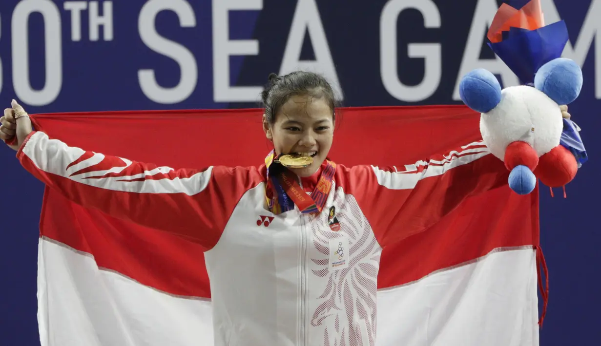 Lifter Windy Aisyah mengibarkan bendera usai mendapatkan medali emas SEA Games 2019 cabang angkat besi nomor 49 kg di Stadion Rizal Memorial, Manila, Minggu (1/12). Dirinya meraih emas dengan total angkatan 104 kg. (Bola.com/M Iqbal Ichsan)