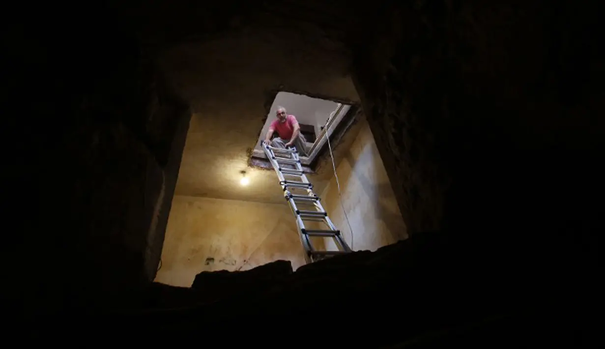 Tal menurunkan tangga ke lorong yang terdapat kolam ritual Yahudi (Mikveh) yang ditemukan di rumahnya, Ein Karem, Yerusalem (1/7/2015). Tal menemukan Mikveh yang diyakini berusia lebih dari 2.000 tahun saat sedang merenovasi rumah.  (AFP/GALI TIBBON)