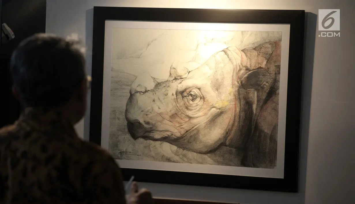Seorang pengunjung melihat-lihat karya dalam pameran seni badak Sumatera di Perpustakaan Nasional Indonesia, Jakarta Pusat, Jumat (19/1). Pameran ini sebagai bentuk upaya pelestarian badak Sumatera yang hampir punah. (Liputan6.com/Arya Manggala)