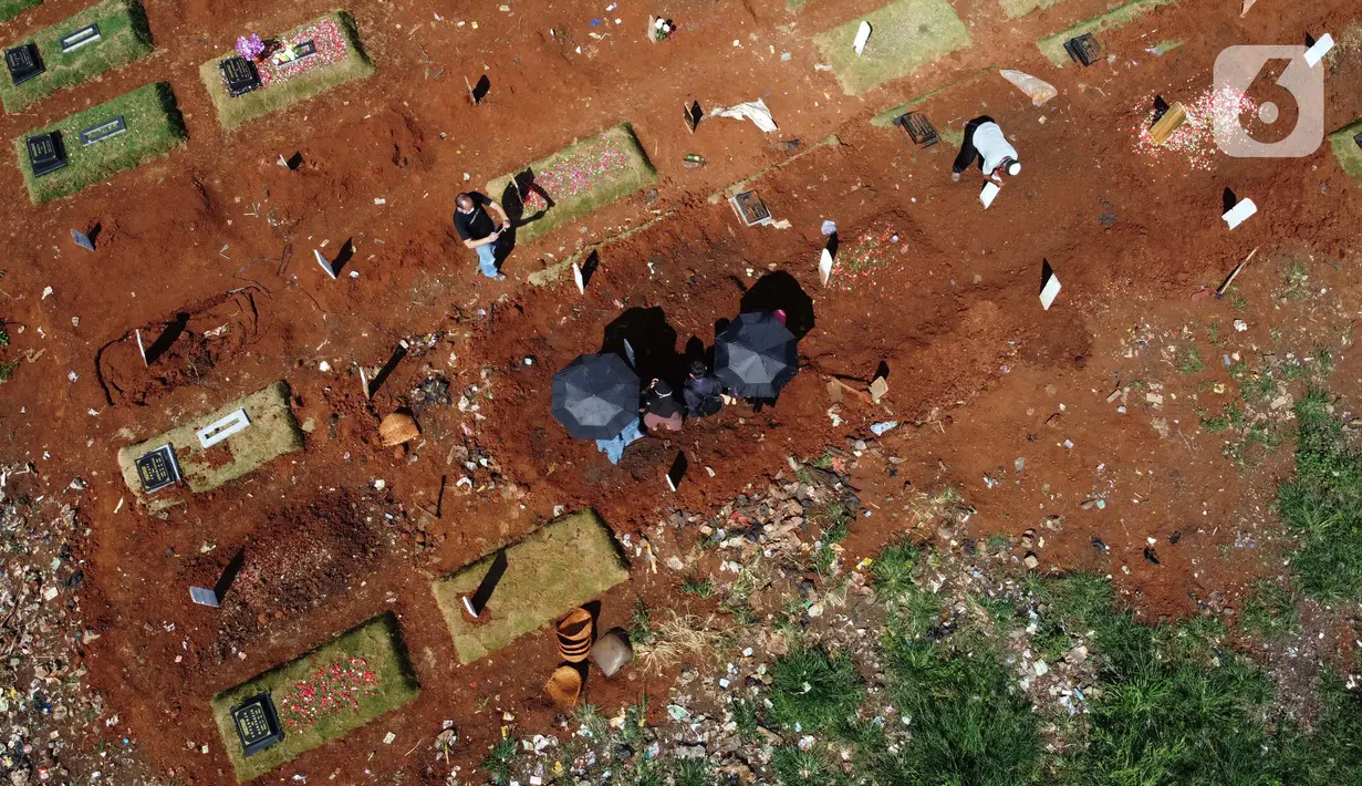Foto aerial peziarah berdoa di sisi makam jenazah yang diduga terinfeksi virus COVID-19 di TPU Pondok Ranggon, Jakarta, Minggu (24/5/2020). Momen Hari Raya Idul Fitri 1441 H dimanfaatkan keluarga dan kerabat korban yang diduga terinfeksi COVID-19 untuk berziarah. (Liputan6.com/Helmi Fithriansyah)
