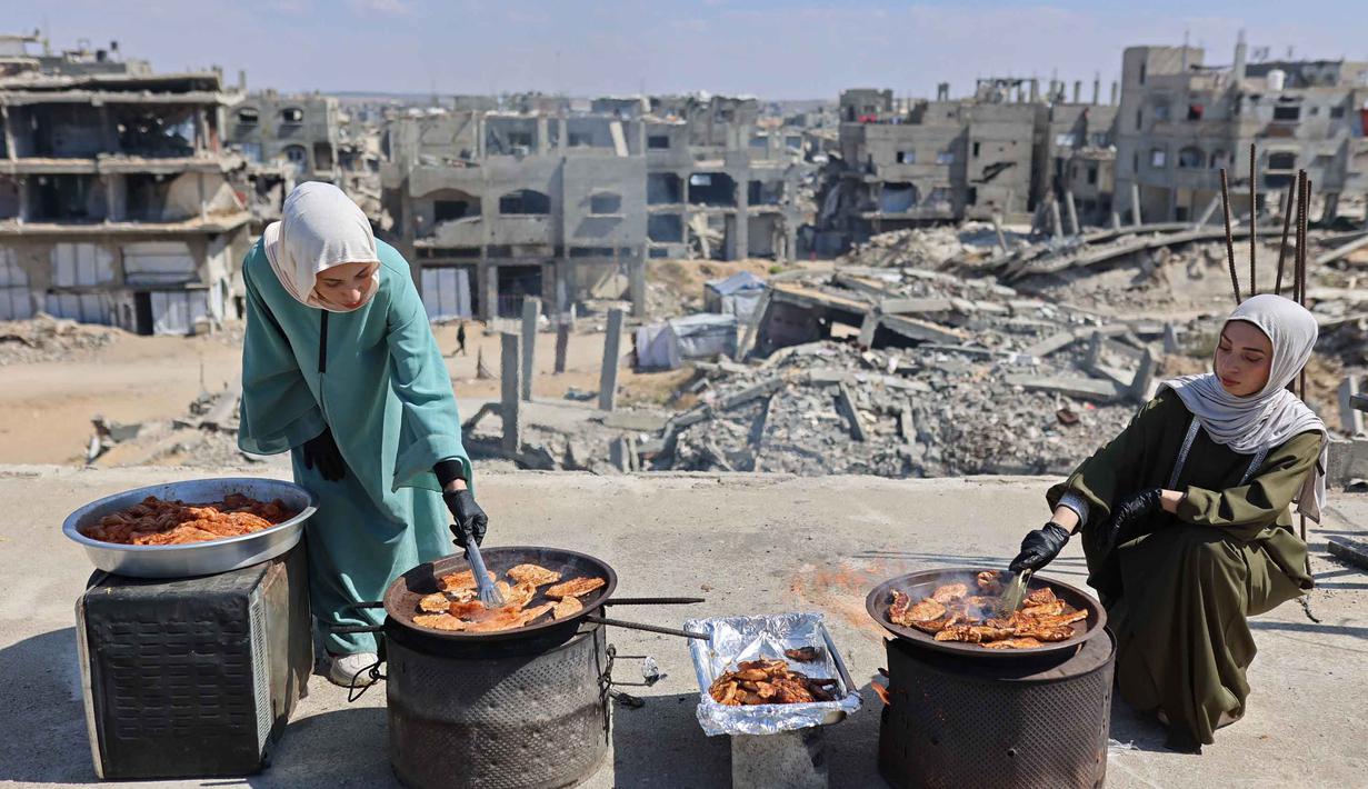 Di tengah krisis kelaparan yang terus mengancam kehidupan di Gaza, kakak beradik Palestina, Lina Zeid dan Aya Zeid, menyalurkan bantuan berupa paket makanan gratis kepada anak-anak pengungsi di daerah Al-Tuam, sebelah barat Jabalia, Jalur Gaza Utara. Tampak dalam foto, kakak beradik Palestina, Lina Zeid (kiri) dan Aya Zeid, menyiapkan makanan di atap rumah mereka untuk dibagikan kepada anak-anak pengungsi sebagai kegiatan amal di daerah Al-Tuam, sebelah barat Jabalia, Jalur Gaza Utara pada Rabu 6 Mei 2026. (Omar AL-QATTAA/AFP)
