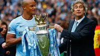 Kapten Manchester City, Vincent Kompany (kiri) bersama Manuel Pellegrini membawa trofi Liga Primer Inggris di Stadion Etihad, Manchester (11/5/2014). (REUTERS/Darren Staples)