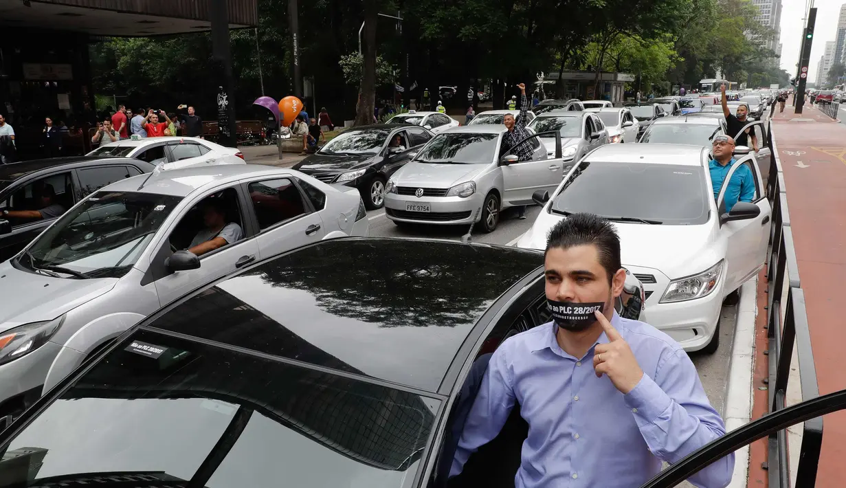 Ratusan pengemudi Uber saat menggelar aksi unjuk rasa memprotes penerapan aturan undang-undang mengenai transportasi di Sao Paulo, Brasil (30/10). Aksi tersebut menimbulkan kemacetan parah di sejumlah jalan. (AP Photo / Andre Penner)