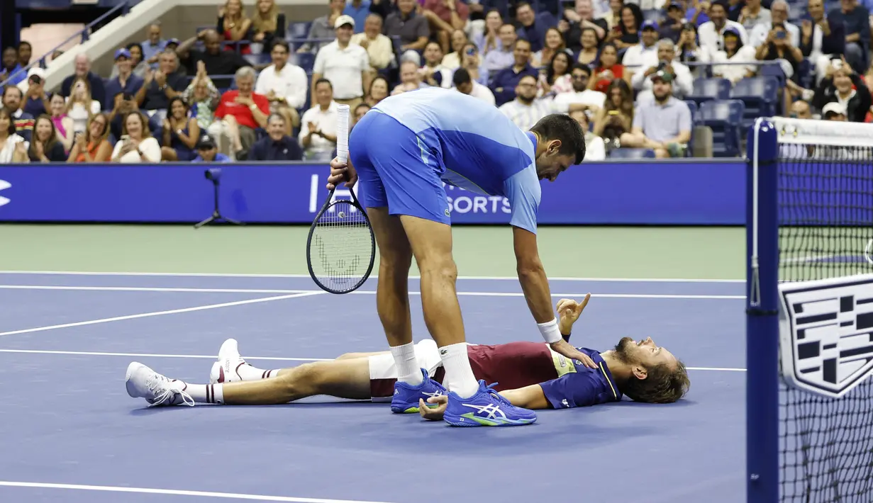 Petenis asal Serbia, Novak Djokovic (atas), menghampiri petenis asal Rusia Daniil Medvedev yang tergeletak di lapangan dalam pertandingan final US Open 2023 yang berlangsung di Arthur Ashe, New York, Senin (11/9/2023) pagi WIB. (AFP/Kena Betancur)