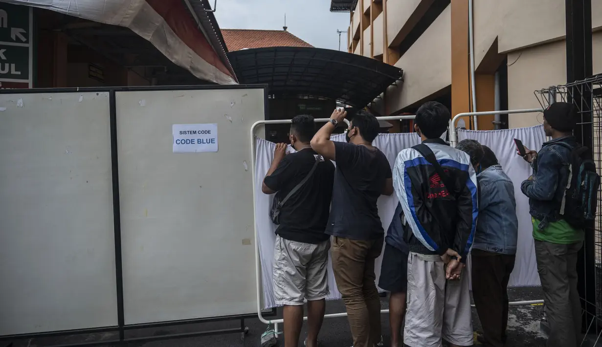 Keluarga dan kerabat korban tragedi Stadion Kanjuruhan menunggu di luar sebuah rumah sakit di Malang, Jawa Timur pada 2 Oktober 2022. Sedikitnya 174 orang tewas di stadion sepak bola Indonesia ketika ribuan penggemar tuan rumah yang marah menyerbu lapangan dan polisi menanggapi dengan gas air mata yang memicu desak-desakan, kata pihak berwenang pada 2 Oktober. (AFP/Juni Kriswanto)