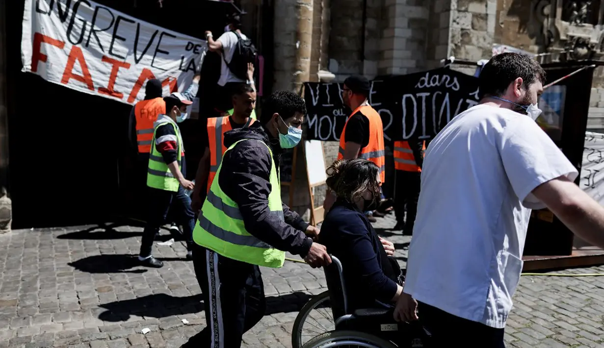 Relawan paramedis mengevakuasi migran yang mogok makan ke rumah sakit saat ia menduduki Gereja Saint-Jean-Baptiste-au-Beguinage di Brussel, Belgia, Rabu (2/6/2021). Para migran menyerukan lebih banyak inisiatif untuk memungkinkan mereka bekerja. (Kenzo TRIBOUILLARD/AFP)