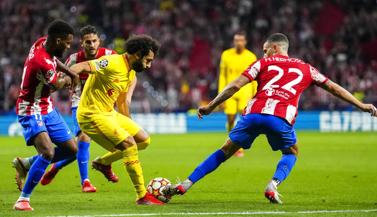 Pemain Liverpool Mohamed Salah (tengah) berduel memperebutkan bola dengan pemain Atletico Madrid Mario Hermoso (kanan) pada pertandingan sepak bola Grup B Liga Champions di Stadion Wanda Metropolitano, Madrid, Spanyol, Selasa (19/10/2021). Liverpool menang 3-2. (AP Photo/Manu Fernandez)