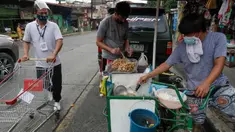 Seorang pria yang mengenakan masker membeli makanan dari warung kaki lima di kota Quezon, Filipina, Selasa (22/9/2020). Presiden Filipina Rodrigo Duterte mengatakan telah memperpanjang status masa darurat virus corona (Covid-19) di negaranya hingga satu tahun ke depan. (AP Photo/Aaron Favila)
