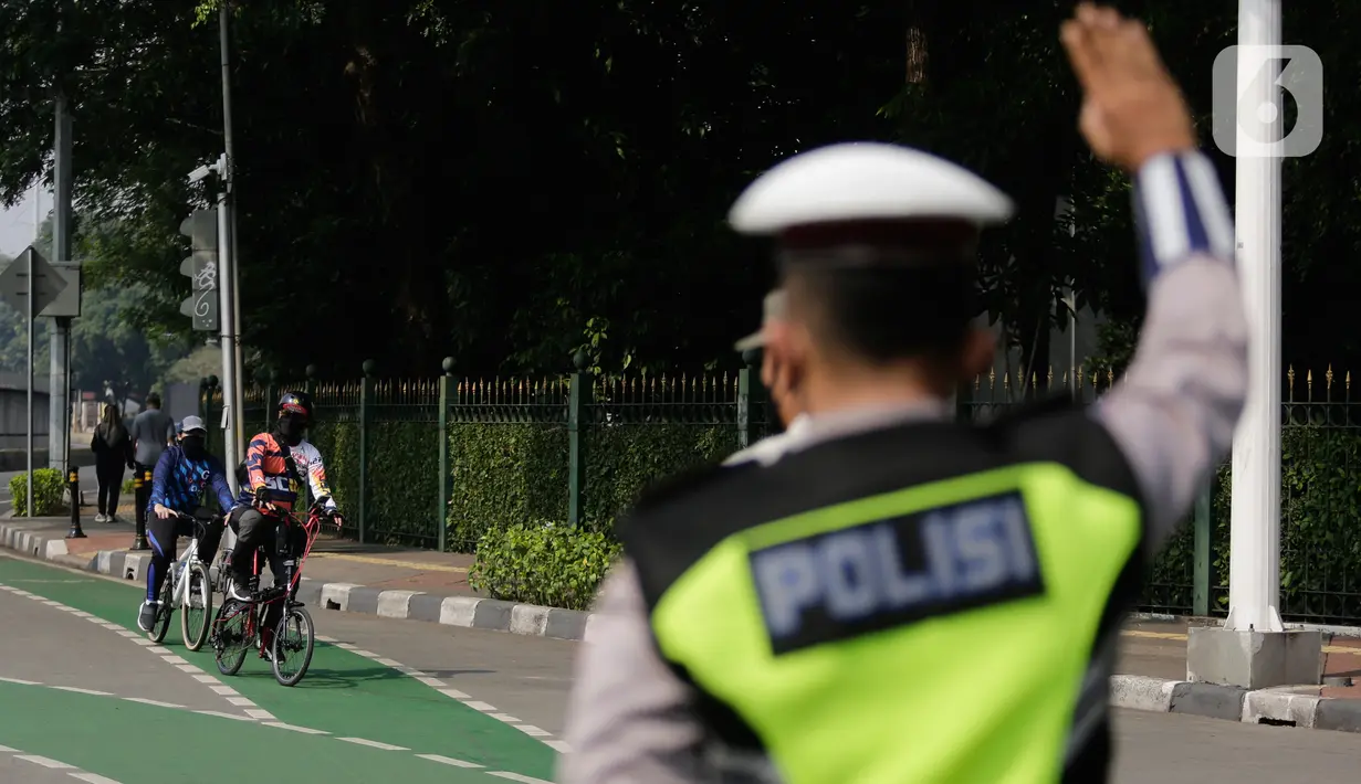 Petugas gabungan mengarahkan pengguna sepeda saat pengalihan jalur pesepeda di kawasan Sudirman-Thamrin, Jakarta, Minggu (5/9/2021). Pemberlakuan jalur ganjil genap pada masa PPKM membuat pengguna sepeda dilarang melintasi kawasan ganjil-genap pagi ini. (Liputan6.com/Angga Yuniar)