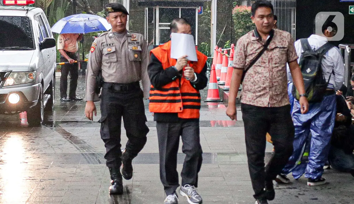 Mengenakan rompi tahanan KPK dan tangan terborgol, Heryanto Tanaka menutupi wajahnya dengan menggunakan kertas yang dia bawa. (Liputan6.com/Faizal Fanani)