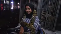 Pritta saat berteduh dari hujan di daerah Kecamatan Kalitidu, Kabupaten Bojonegoro, mengalungkan ular piton di tubuhnya. (Liputan6.com/Ahmad Adirin)