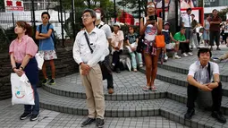 Sejumlah warga menyaksikan video pidato Kaisar Jepang Akihito, yang ditayangkan di layar lebar di Tokyo, Jepang. (8/8). Video rekaman pidato berdurasi 10 menit ini ditayangkan di stasiun televisi nasional. (REUTERS/Kim Kyung-Hoon)