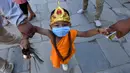 Seorang anak mengenakan kostum tradisional dan masker saat berpartisipasi dalam prosesi 'Gai Jatra', atau festival sapi, di Kathmandu, Nepal, Selasa (4/8/2020). Sapi dianggap sebagai hewan suci bagi pemeluk Hindu yang membantu jiwa-jiwa yang telah pergi mencapai surga. (PRAKASH MATHEMA/AFP)