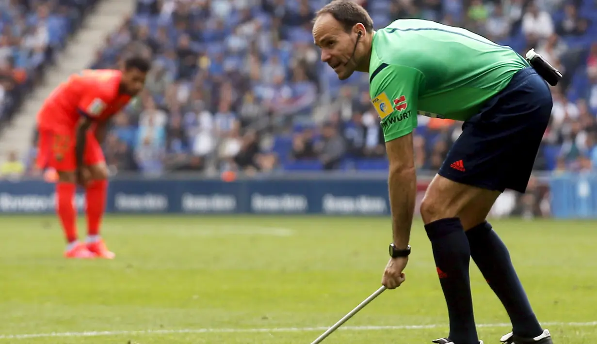 Wasit Antonio Mateu mengambil tongkat yang dilemparkan ke dalam stadion (REUTERS/Gustau Nacarino).